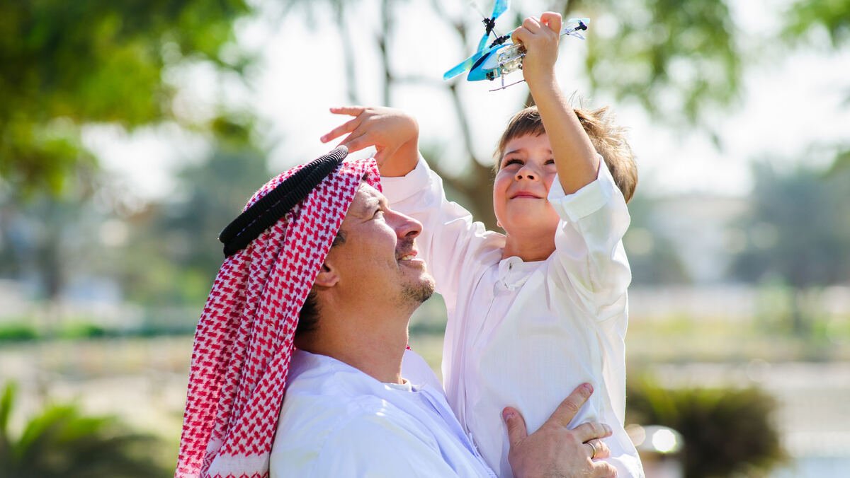 أب يحمل ابنه ويلعبان معاً في الحديقة